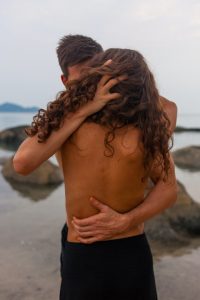 pareja semidesnuda abrazandose al borde del mar