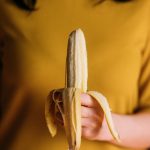 mujer sosteniendo un plátano pelado